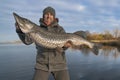 Success pike fishing. Happy fisherman hold huge muskie fish