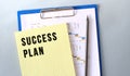 SUCCESS PLAN text written on notepad with pencil. Notepad on a folder with diagrams. Royalty Free Stock Photo