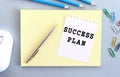 SUCCESS PLAN is written on a piece of paper that lies on a notebook next to office supplies Royalty Free Stock Photo