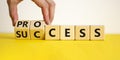 Success process symbol. Businessman turns wooden cubes and changes the word `success` to `process`. Beautiful yellow table, wh