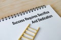 Success requires sacrifice and dedication text written on a spiral notepad with ladder illustration highlighting determination Royalty Free Stock Photo