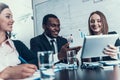 Success smiling woman shows something on computer tablet to black businessman at business meeting. Royalty Free Stock Photo