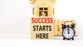 Success starts here symbol. Concept word Success starts here on beautiful wooden block. Black alarm clock. Beautiful white Royalty Free Stock Photo