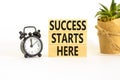 Success starts here symbol. Concept word Success starts here on beautiful wooden block. Black alarm clock. Beautiful white Royalty Free Stock Photo