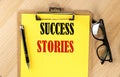 SUCCESS STORIES text on a yellow paper on wooden background