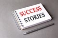 SUCCESS STORIES word on notebook on grey background