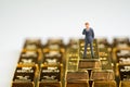 Success wealth management concept, miniature figure businessman standing on stack of shiny gold bar bullions ingot with copy space Royalty Free Stock Photo