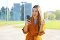 Success woman celebrating outdoor cheering and raising her fist up in exultation. Excited fashion woman watching her phone in the