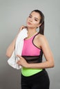 Successful active fit woman wearing sportsuit holding white towel after workout against gray studio wall background