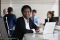 Successful African businesswoman posing sit at desk in office Royalty Free Stock Photo