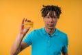 Successful african man showing unlimited gold credit card on yellow studio. Royalty Free Stock Photo