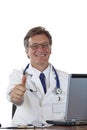 Successful aged doctor at desk holds thumb up Royalty Free Stock Photo