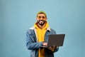 Successful arab freelancer guy using laptop computer and smiling to camera while standing over blue background Royalty Free Stock Photo