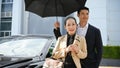 Successful Asian aged businesswoman with handsome male bodyguard under the umbrella