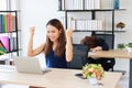 Successful Asian business woman raising hands with competitor colleague bend down head on the desk in office. Royalty Free Stock Photo