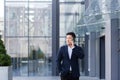 Successful Asian businessman businessman talking on a mobile phone while walking near the office of a large modern, serious and
