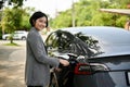 A successful Asian businesswoman charging her electric car at a public charger station Royalty Free Stock Photo