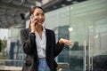 Successful Asian businesswoman is on the phone while walking outside along the company building Royalty Free Stock Photo