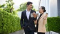 Asian male banker or businessman talking with aged businesswoman outside of the building