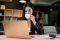 Successful asian businesswoman sipping a hot coffee while working on her task on laptop Royalty Free Stock Photo