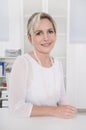 Successful attractive blond older businesswoman sitting at desk. Royalty Free Stock Photo