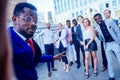 Successful and beautiful American afro man in a business suit in a white shirt looking into the phone and takes photos