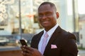 Successful and beautiful American afro man in a dark business suit in a white shirt looking into the phone standing on Royalty Free Stock Photo