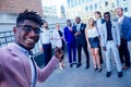 Successful and beautiful American afro man in a business suit in a white shirt looking into the phone and takes photos