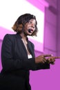 Successful black African American business woman with headset speaking in auditorium at corporate training event or seminar giving Royalty Free Stock Photo