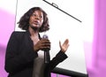 Successful black afro American business woman with headset speaking in auditorium at corporate training event or seminar giving Royalty Free Stock Photo