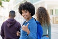 Successful black female student with backpack and friends showing thumb up Royalty Free Stock Photo