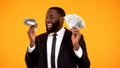 Successful black man in business suit holding bunches of dollar cash and smiling Royalty Free Stock Photo