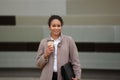 Successful business African American woman realtor in coat walks with folder with documents for office and cup of tea or Royalty Free Stock Photo