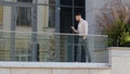 Successful business man boss leader worker manager well-dressed guy walks on balcony terrace in company office looking