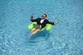 Successful business man floating in suit in pool water. Summer vacations and travel concept. Funny business man drink Royalty Free Stock Photo