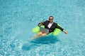 Successful business man floating in suit in pool water. Summer vacations and travel concept. Funny business man drink Royalty Free Stock Photo