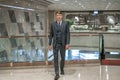 Successful business man in grey classic suit walking in shopping mall. Royalty Free Stock Photo