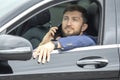 Successful business man with a phone in his hand sits behind the wheel of a prestigious car Royalty Free Stock Photo