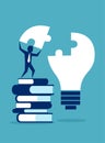 Successful business man standing on pile of books completing light bulb puzzle Royalty Free Stock Photo