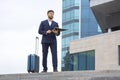 Successful business man stands on the steps against the background of an office business building with documents in his hands Royalty Free Stock Photo