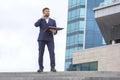 Successful business man stands on the steps against the background of an office business building with documents in his hands Royalty Free Stock Photo