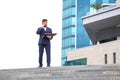 Successful business man stands on the steps against the background of an office building with documents in his hands Royalty Free Stock Photo