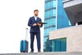 Successful business man stands on the steps against the background of an office building with documents in his hands Royalty Free Stock Photo