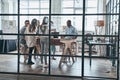 Successful business team. Full length of young confident business people discussing something while working behind the glass wall