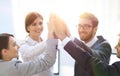 Successful business team giving each other a high-five, standing in the office Royalty Free Stock Photo