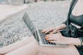 Successful business woman with bright red manicure typing on laptop keyboard outdoors on beach with sea view. Close up Royalty Free Stock Photo