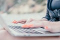 Successful business woman with bright red manicure typing on laptop keyboard outdoors on beach with sea view. Close up Royalty Free Stock Photo