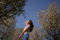 Successful business woman enjoys her leisure free time in a park with blossoming sakura cherry trees wearing jeans, pink