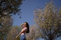 Successful business woman enjoys her leisure free time in a park with blossoming sakura cherry trees wearing jeans, pink