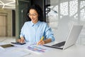 Successful business woman financier on paper work with contracts and reports works sitting at workplace,hispanic smiling Royalty Free Stock Photo
